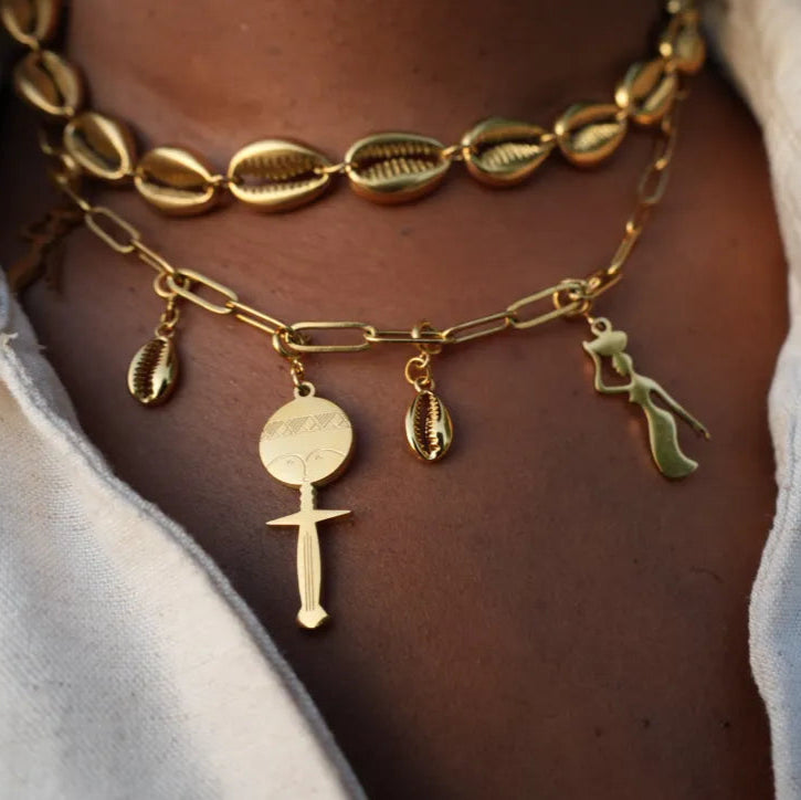 Close-up of a person wearing multiple gold necklaces with various charms. FArican charms